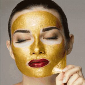 Fair-skinned woman with dark-brown hair peeling off a gold face mask